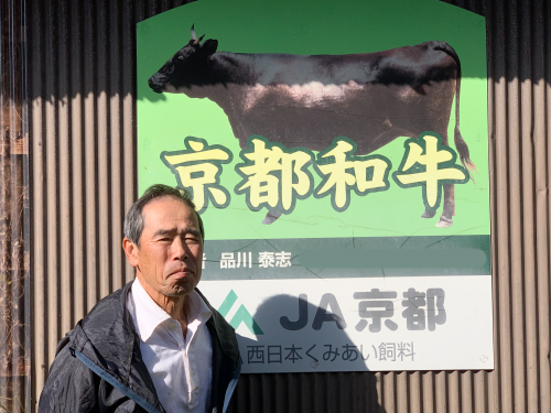 品川さんが看板の前にたっている