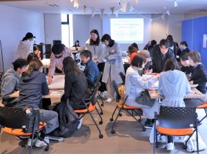 いくつかのテーブルに男女数名が話し合っている様子。