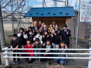 新しいバス待合所の前で小学生、高校生、地域の方20名ほどの笑顔の様子