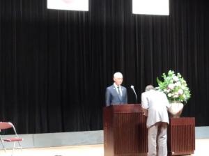 壇上で市長から学習ノートを受け取る男性