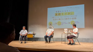 3人の登壇者の男性がステージ上で椅子に座っている様子