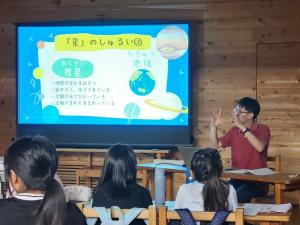 星や宇宙について話を聞く3~4名ほどの子供と向かい合って座る講師