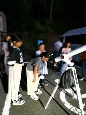 外で天体望遠鏡で夜空を観測する参加者